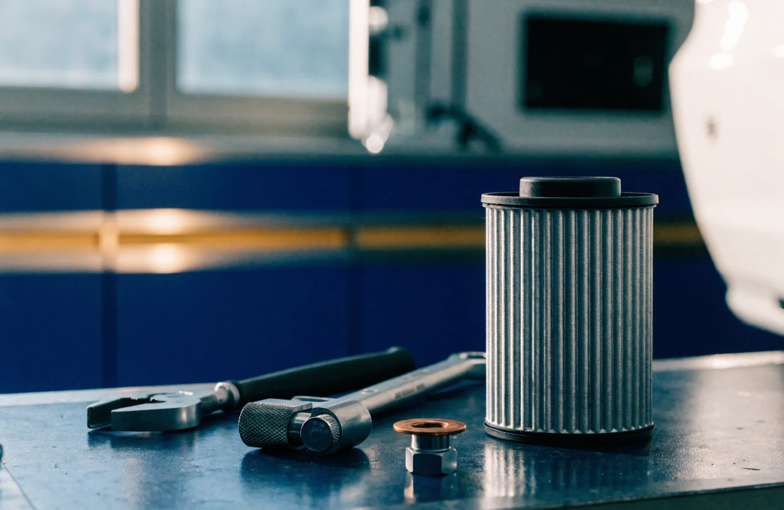 New oil filter element, wrenches, and a copper crush washer on a service workbench