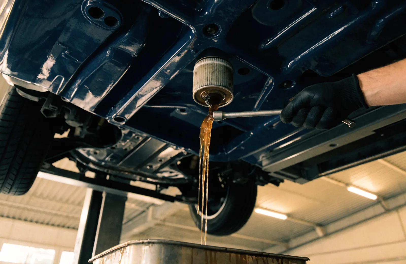 Used oil draining from the filter into a catch pan with the car on a service lift